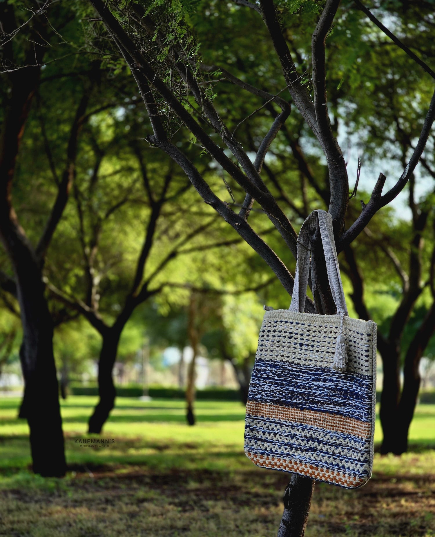 Jute Tote Bag hanged in a branch at a park with a scenic view of greenery.